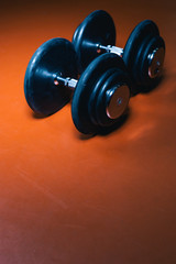 Fototapeta na wymiar Photo of dumbells on a gym floor. Dumbells with centered light. Focus in center.