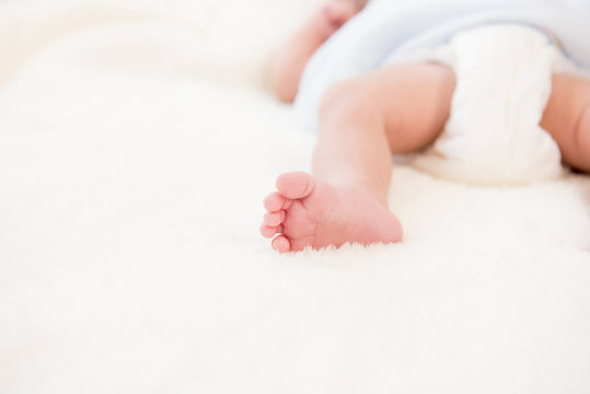 Small little foot of newborn baby on soft white wool sheet