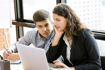 Obraz premium Business woman and her fellow worker looking at laptop computer, working together