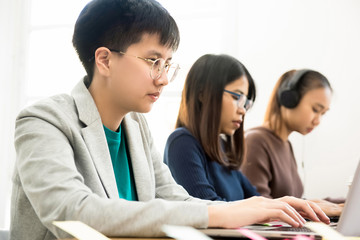 College Asian students concentrating on using laptop computers
