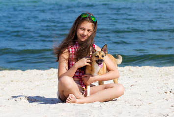 Girl gently stroking the dog on the sea beach