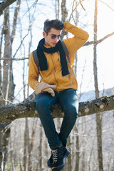 Hiker man with backpack and sleeping bag walking in the mountains in winter at sunset time. Enjoying the nature concept.