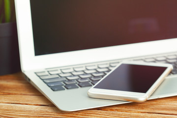 office desk with laptop smart phone and business office background.
