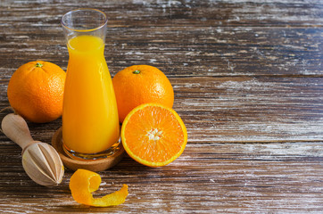 Freshly squeezed orange juice, organic oranges fruit cut in half  with peels  and  wooden citrus juicer on dark wooden table.Copy space.