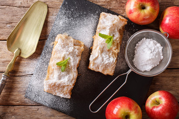 German apple strudel with powdered sugar and mint closeup on a table. Horizontal top view