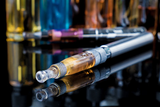 Electronic cigarette with e-liquid bottles in background