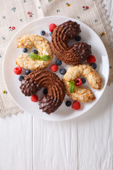 Almond and chocolate cookies in the shape of a horseshoe with fresh berries close-up. vertical top view