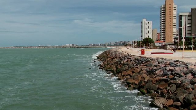 Shot from pier English Bridge of waves crashing to stone waterfront of Fortaleza, Brazil