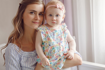 Closeup portrait of beautiful white Caucasian woman mother holding cute adorable blonde baby girl daughter with large blue eyes looking in camera,  family lifestyle, motherhood concept