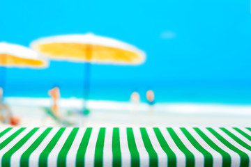 Table top covered with striped tablecloth on blurred summer beach background