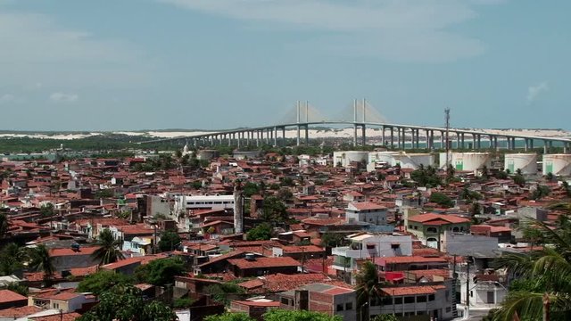 Wide shot of cable-stayed Newton Navarro Bridge in Natal, Brazil with red tiles houses in front