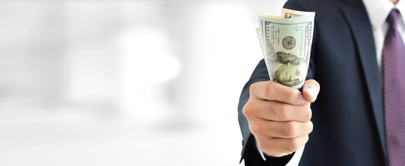 Businessman holding money,   united states dollar (USD) bills, on blur white gray background
