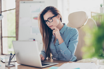 Close up portrait of serious young business lady economist in formal wear and with glasses, sitting...