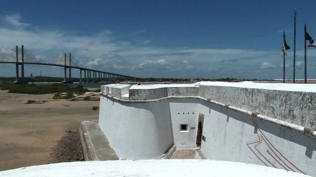 Shot of white thick wall of Fort dos Reis Maos in Natal, Brazil. Newton Navarro Bridge on the background 