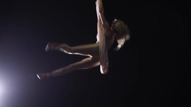 Woman aerial gymnast performing on silk in circus stage. Exciting acrobatic show.