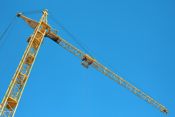 A yellow crane and a blue cloudless sky.