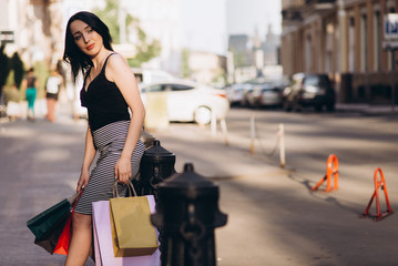 Fashionably dressed woman with colored shopping bags, shopping concept