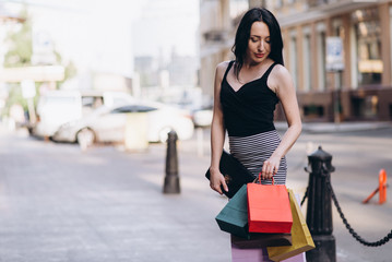 Fashionably dressed woman with colored shopping bags on the streets, shopping concept