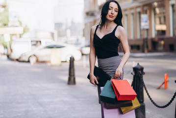 Fashionably dressed woman with colored shopping bags on the streets, shopping concept