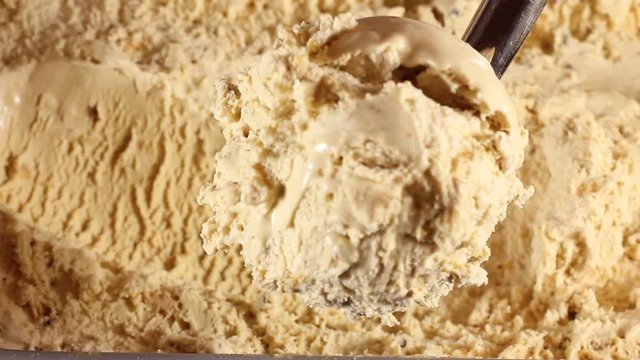 strawberry ice cream scooped out of container spoon is a ball. Close-up of caramel ice cream in a large box. Round spoon makes shoelaces balls for buyers