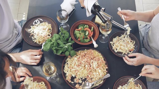 Group of young people eating traditional Italian pasta .