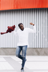 Handsome Afro American man wearing casual clothes jumping and dancing with grunge concrete wall background