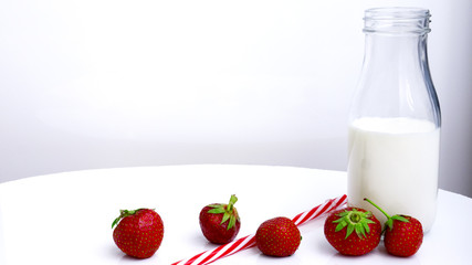 bottle with milk and strawberries on a white background