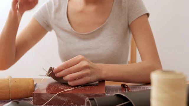 Woman making leather wallet at home