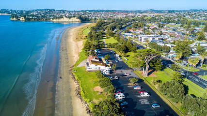 Aerial view on sunny beach with car parking. Auckland, New Zealand.