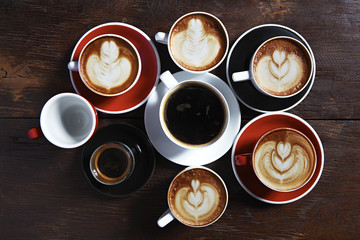 Many cups of coffee on wooden table, top view
