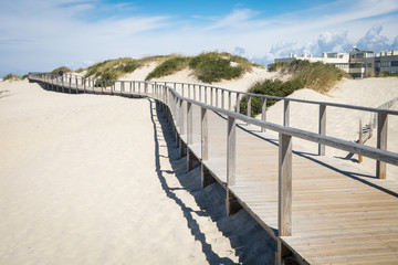 Wooden promenade at european sandy beach near sea with running man, Beach in portugal, Jogging trail, Sand dunes with a wooden footbridge for pedestrians