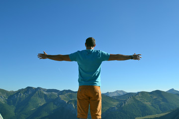 Silhouette man with hands rise up on beautiful view, upon the top of mountain. Concept freedom of life.