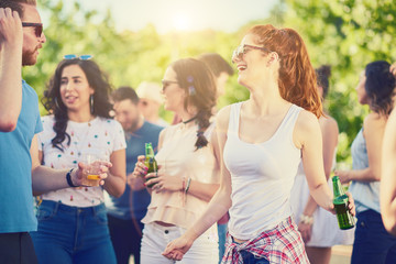 Group of friends drinking, chatting and having a good time at outdoor party