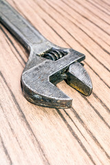 Old universal adjustable wrench on a wooden background. Closeup Bench tool. Blurred background.
