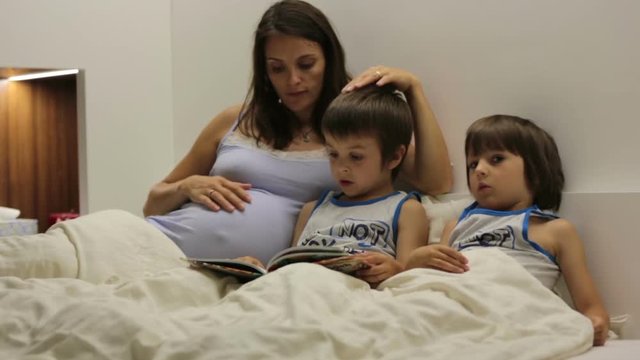 Pregnant mum, reading bedtime story for her sons