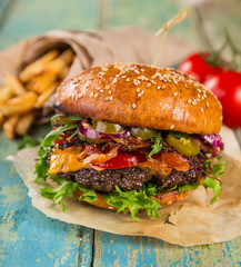 Big tasty burger served on old wooden table.