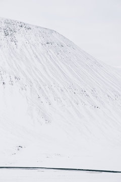 Icelandic winter minimalism: Lonely snowy mountain and a wild glacial river flowing on its foot