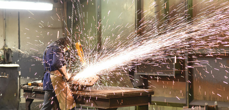 Industriearbeiter mit Schleifmaschine bearbeitet Werkst&uuml;ck