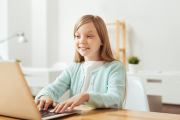 Bright energetic child typing something on her laptop