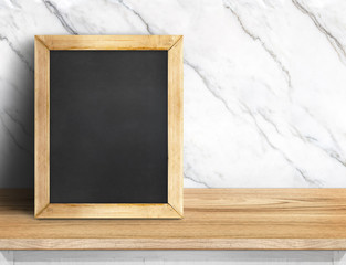 Blank blackboard on wood table at white marble wall,Template mock up for adding your design and leave space beside frame for adding more text.