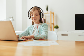 Inspired lively girl listening to music while studying
