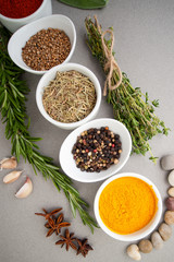 Various dry spices and spicy herbs close-up on a light gray table..