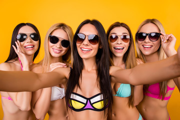 Selfie time, ladies! Five girlfriends in fashionable different swim suits and sunglasses are posing for a selfie photo, that brunette is taking. They are all with beaming smiles,, making memories