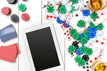 Gambling. Poker chips, cards and the dice nearby tablet on wooden table. Top view. Copyspace. Poker