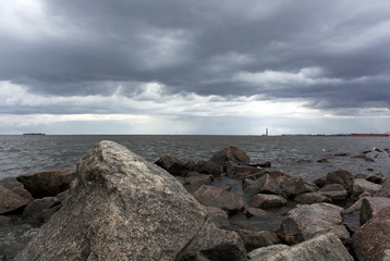 Fototapeta na wymiar stones, boulders in the water, the Gulf coast, rain clouds in the sky