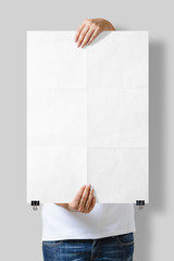 Woman holding a blank A2 poster mockup isolated on a gray background. 
