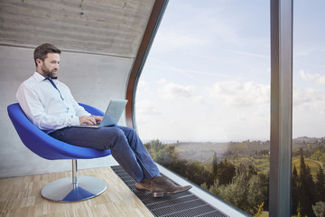 Businessman sitting on chair in attic office using laptop
