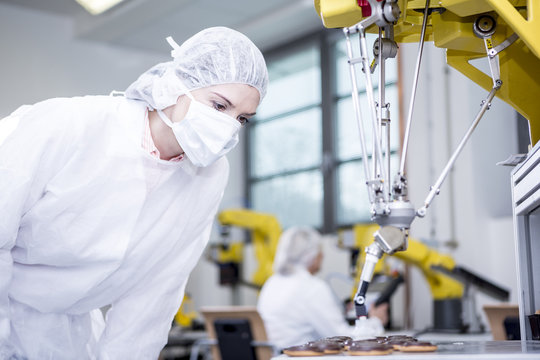 Woman in factory examining robot handling cookies