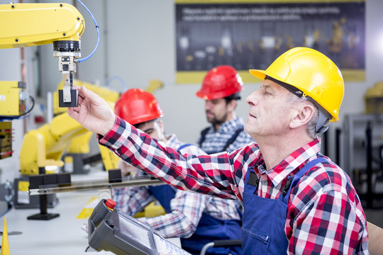 Man wearing hard hat adjusting industrial robot