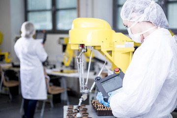 Woman in factory examining robot handling cookies
